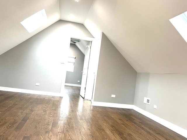 additional living space with dark hardwood / wood-style flooring, ceiling fan, and vaulted ceiling with skylight