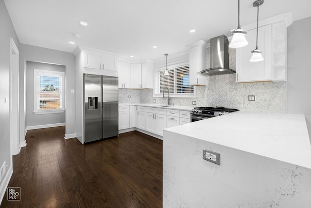 kitchen with white cabinets, appliances with stainless steel finishes, pendant lighting, and wall chimney exhaust hood