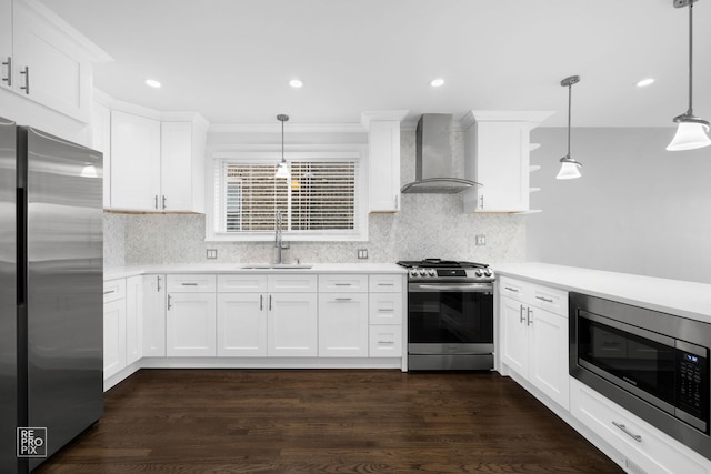 kitchen featuring wall chimney range hood, sink, decorative light fixtures, dark hardwood / wood-style flooring, and stainless steel appliances