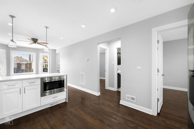 kitchen with white cabinetry, stainless steel microwave, ceiling fan, and dark wood-type flooring