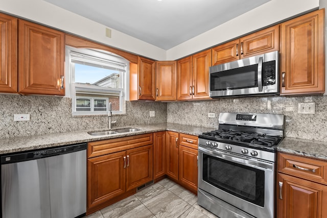 kitchen featuring decorative backsplash, light stone countertops, sink, and appliances with stainless steel finishes