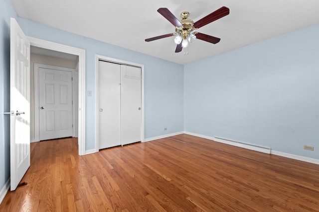 unfurnished bedroom with ceiling fan, a closet, light wood-type flooring, and a baseboard heating unit