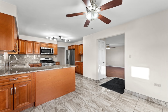 kitchen with kitchen peninsula, appliances with stainless steel finishes, decorative backsplash, sink, and stone counters