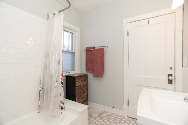 bathroom with tile patterned floors, shower / bath combo with shower curtain, and sink