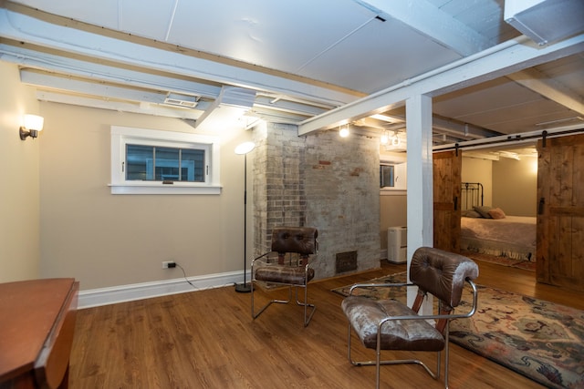 sitting room with a barn door and wood-type flooring