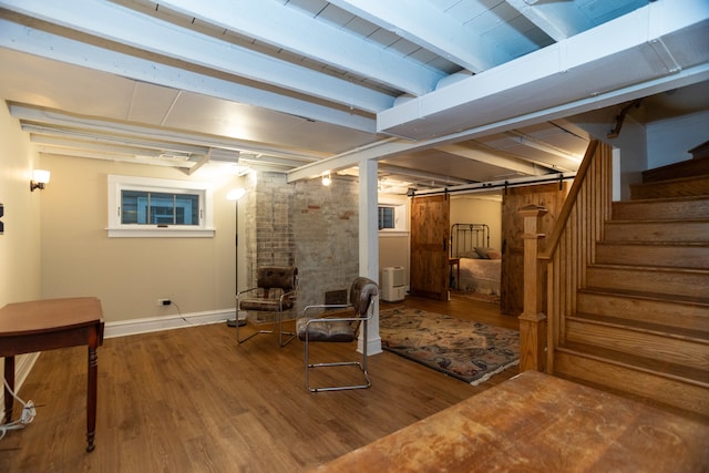 basement with hardwood / wood-style flooring, a barn door, and brick wall