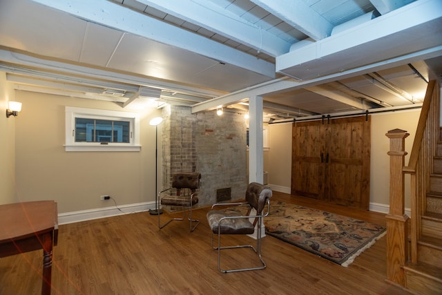 basement with a barn door and hardwood / wood-style flooring