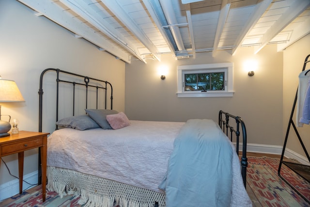 bedroom featuring beam ceiling and hardwood / wood-style flooring