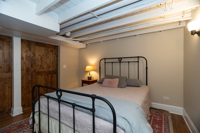 bedroom featuring beamed ceiling and hardwood / wood-style flooring