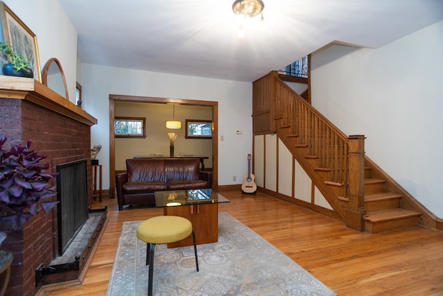 living room with a healthy amount of sunlight, light wood-type flooring, and a brick fireplace