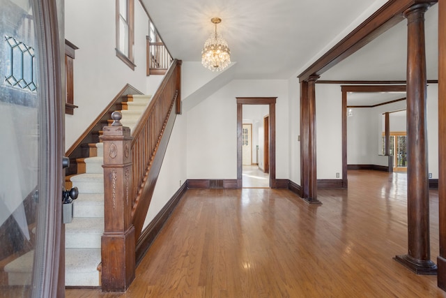 entryway featuring hardwood / wood-style flooring, a notable chandelier, and ornate columns