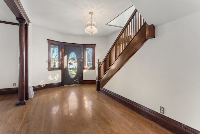 foyer with decorative columns, dark hardwood / wood-style flooring, and a notable chandelier