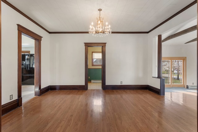 spare room with a baseboard heating unit, wood-type flooring, ornamental molding, and a chandelier