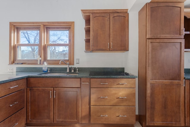 kitchen featuring black cooktop, dark stone countertops, and sink