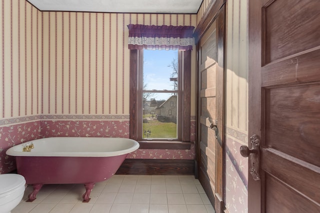 bathroom with tile patterned flooring, a bath, and toilet