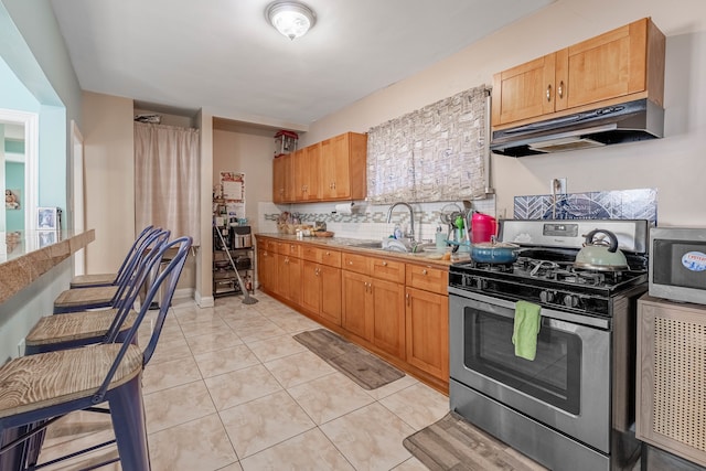 kitchen featuring decorative backsplash, light tile patterned flooring, stainless steel range with gas cooktop, and sink