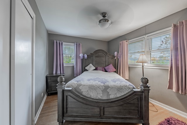 bedroom featuring a closet, hardwood / wood-style flooring, multiple windows, and ceiling fan