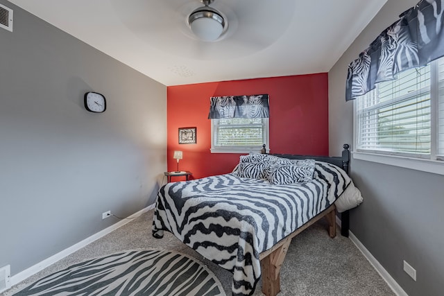 carpeted bedroom featuring multiple windows and ceiling fan