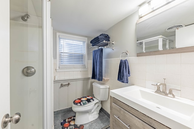 bathroom with tile patterned floors, an enclosed shower, toilet, vanity, and tile walls