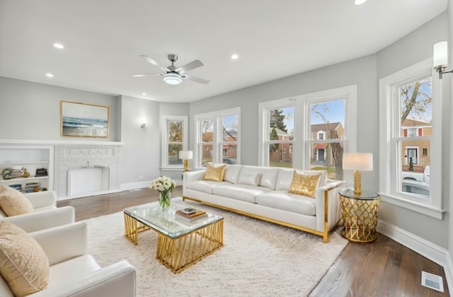 living room with ceiling fan, hardwood / wood-style floors, and a brick fireplace