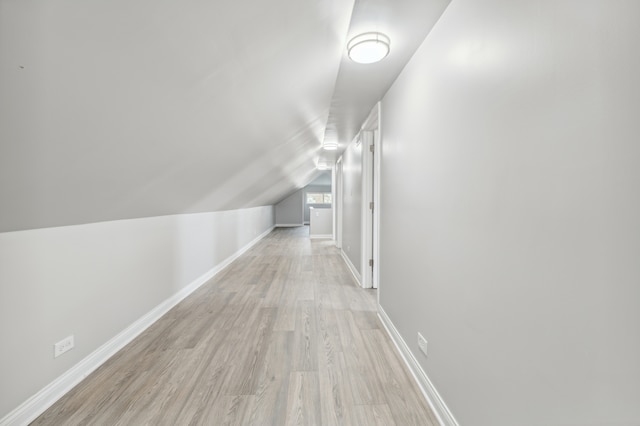 hall with light hardwood / wood-style flooring and lofted ceiling