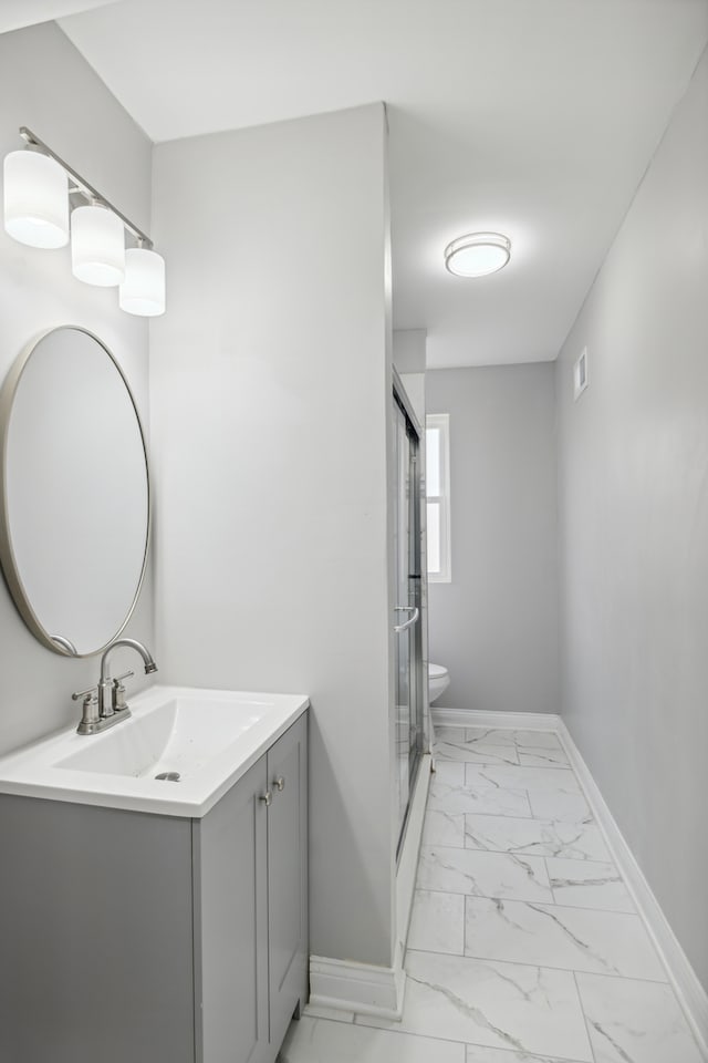 bathroom featuring vanity, an enclosed shower, and toilet