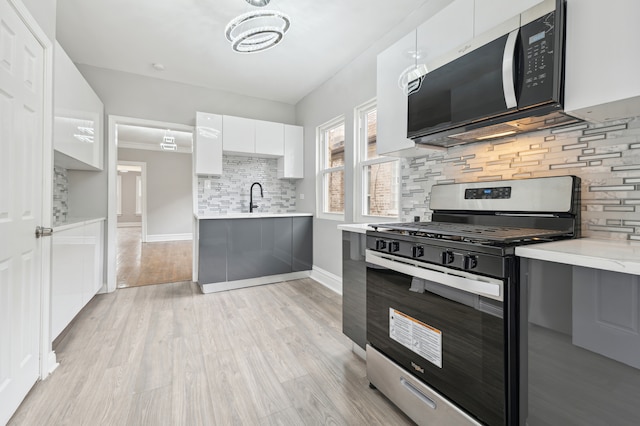 kitchen featuring backsplash, sink, light hardwood / wood-style flooring, white cabinetry, and stainless steel range with gas stovetop