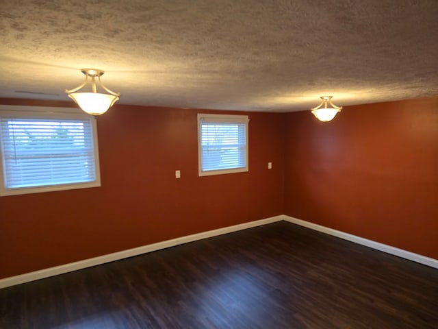 spare room with a textured ceiling and dark wood-type flooring