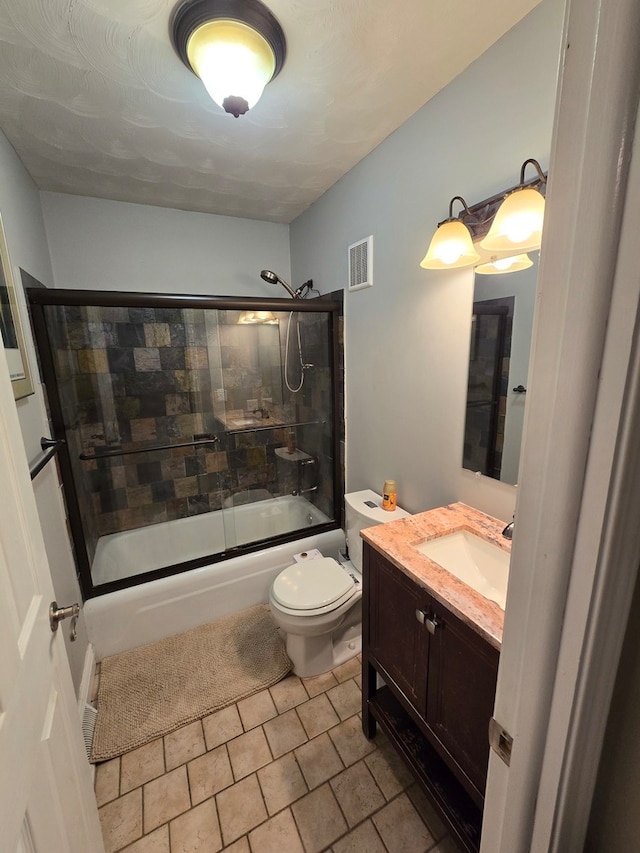 full bathroom with tile patterned floors, vanity, toilet, and bath / shower combo with glass door