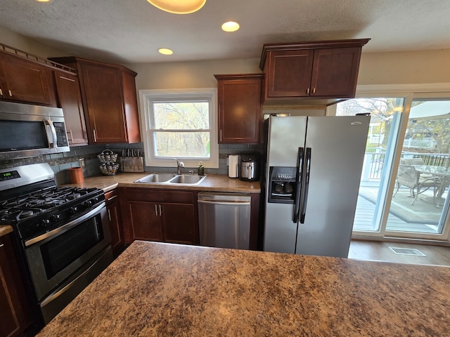 kitchen featuring hardwood / wood-style floors, appliances with stainless steel finishes, backsplash, and sink