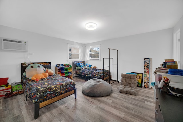 bedroom with a wall unit AC and light hardwood / wood-style flooring