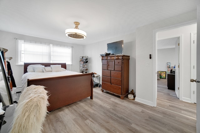 bedroom with light hardwood / wood-style floors and a baseboard radiator