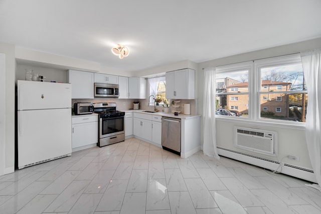 kitchen featuring sink, stainless steel appliances, a baseboard heating unit, backsplash, and white cabinets