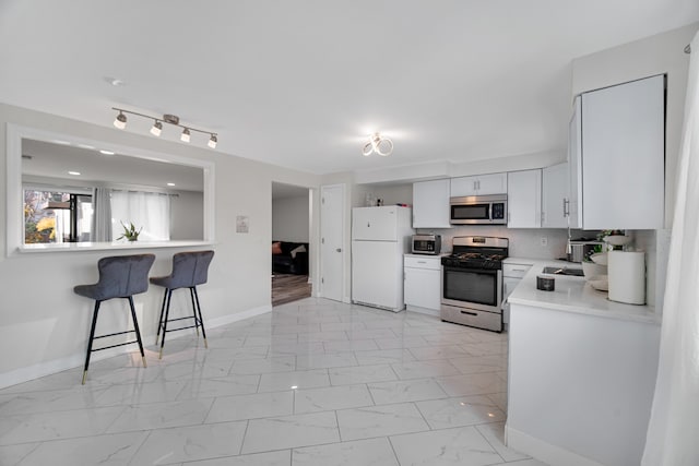 kitchen with white cabinets, decorative backsplash, stainless steel appliances, and a breakfast bar area