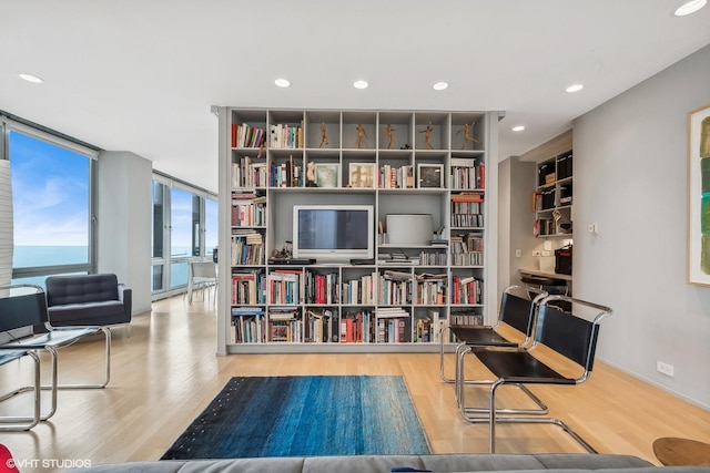 sitting room featuring a water view, expansive windows, and light hardwood / wood-style floors