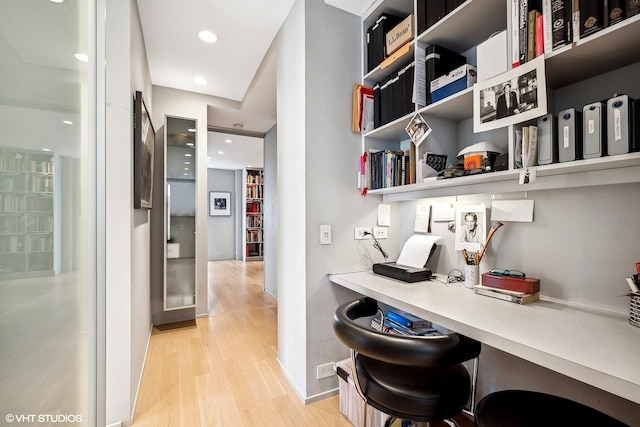 home office with light wood-type flooring and built in desk