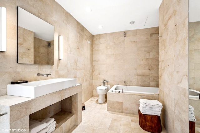 bathroom with sink, tile patterned flooring, a relaxing tiled tub, toilet, and tile walls