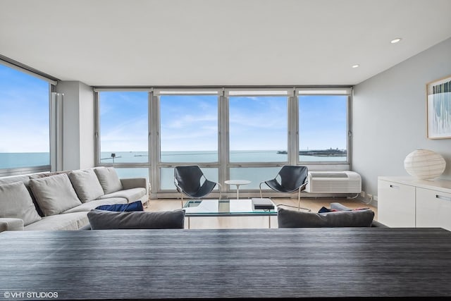 living room featuring hardwood / wood-style floors, expansive windows, a water view, and a wealth of natural light