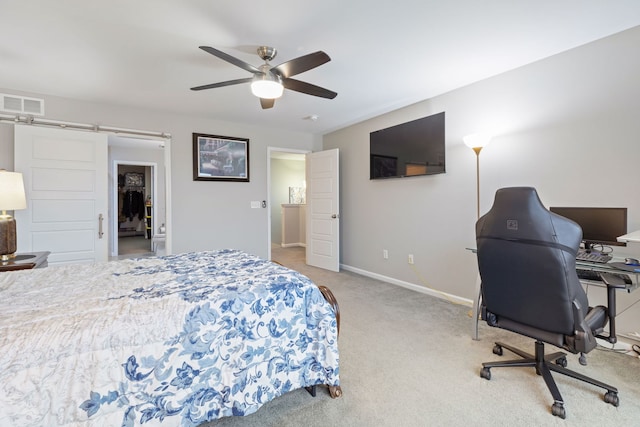 bedroom featuring a barn door, light colored carpet, and ceiling fan