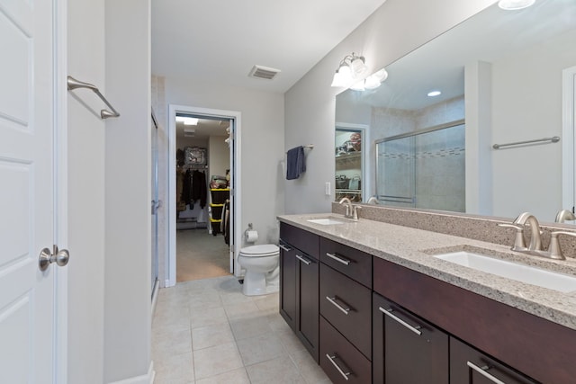 bathroom featuring tile patterned flooring, vanity, toilet, and an enclosed shower