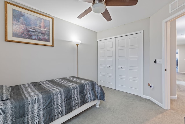 bedroom with ceiling fan, light carpet, and a closet