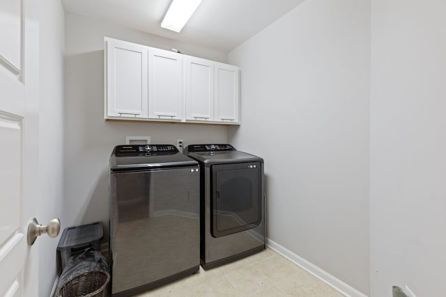 clothes washing area with cabinets and washing machine and dryer