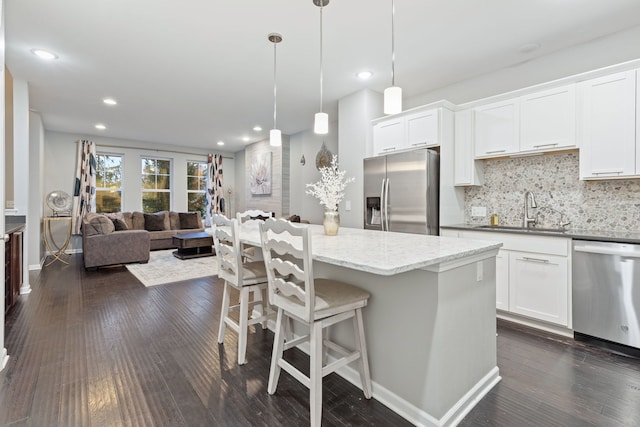 kitchen featuring white cabinetry, sink, pendant lighting, decorative backsplash, and appliances with stainless steel finishes