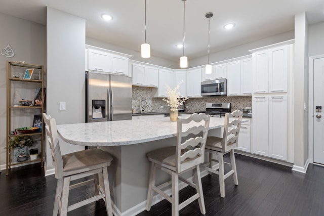 kitchen featuring white cabinets, tasteful backsplash, decorative light fixtures, dark hardwood / wood-style flooring, and stainless steel appliances