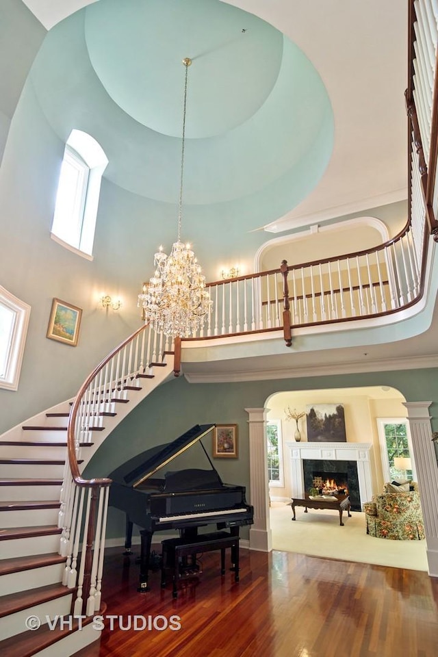 staircase featuring decorative columns, a high ceiling, and a fireplace