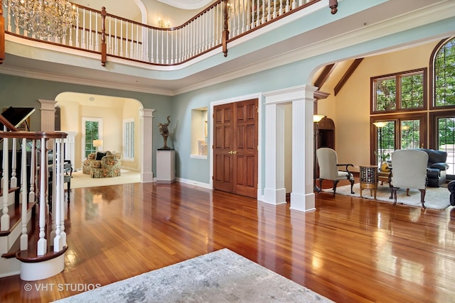 foyer with a high ceiling, hardwood / wood-style floors, and ornate columns