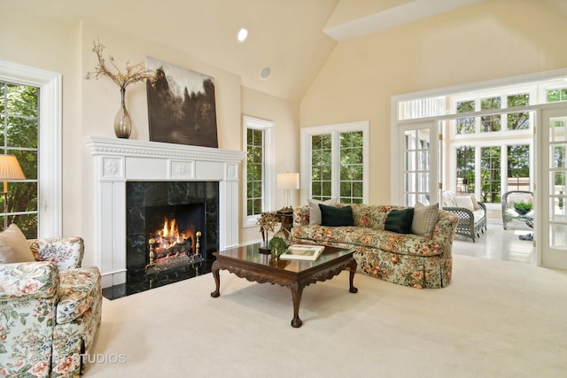 carpeted living room with high vaulted ceiling and a premium fireplace