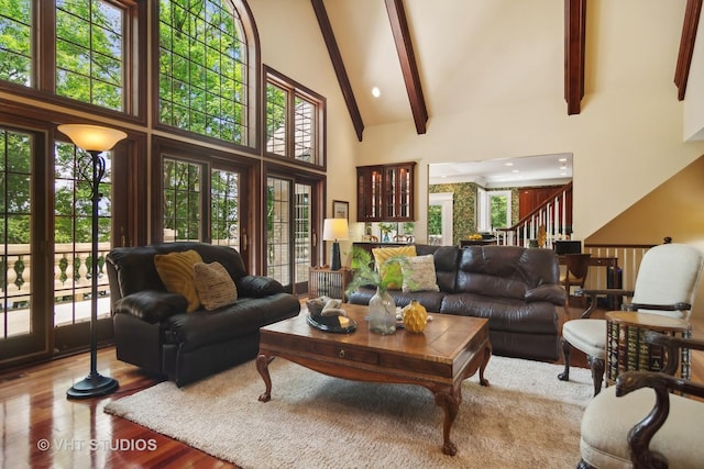 living room with beam ceiling, light hardwood / wood-style floors, and a high ceiling