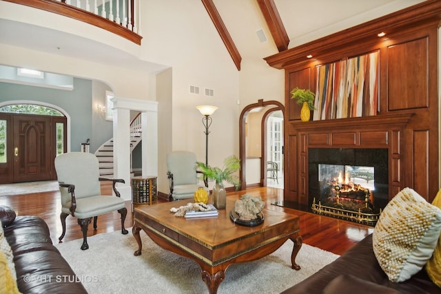 living room with high vaulted ceiling, beam ceiling, a multi sided fireplace, and light hardwood / wood-style flooring