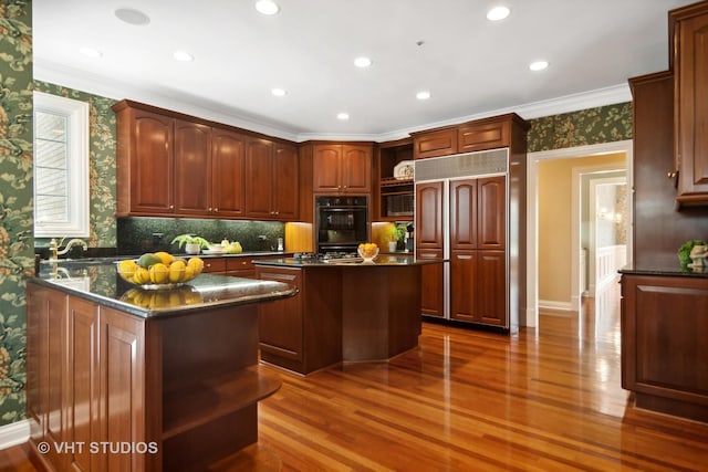 kitchen with dark hardwood / wood-style floors, a kitchen island, crown molding, double oven, and paneled built in fridge